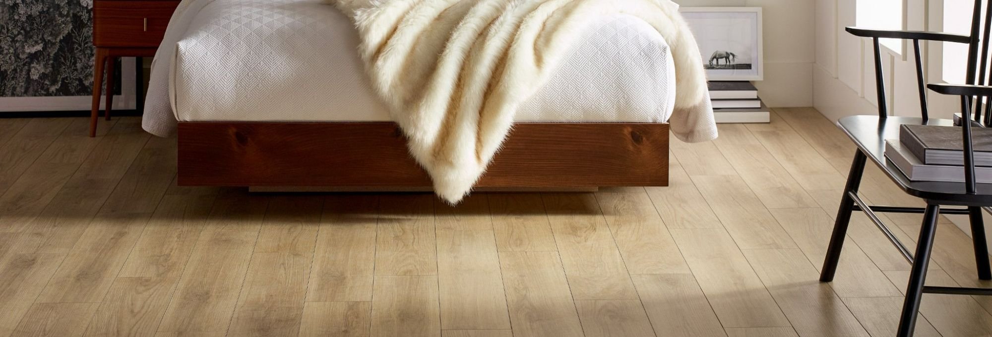 red and white bed on a brown vinyl floor from Wholesale Flooring and Blinds in Casper, WY