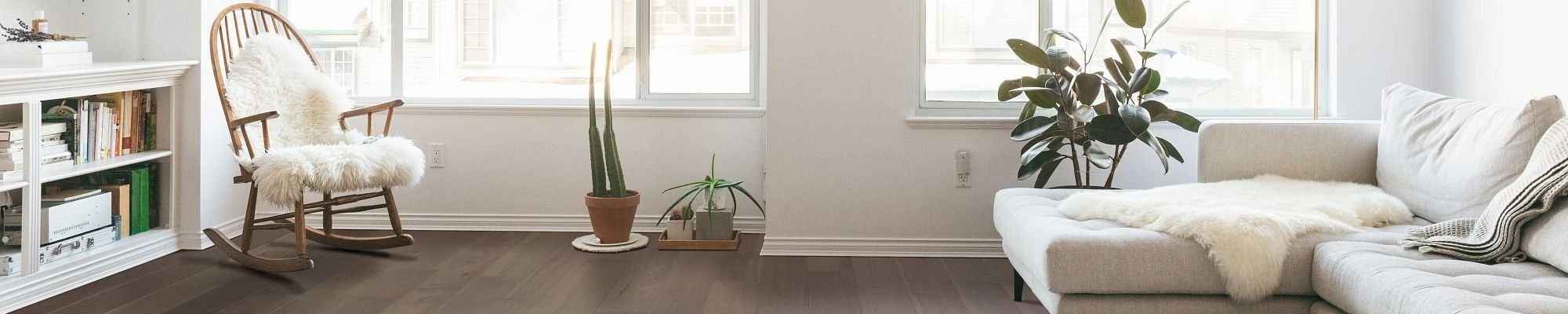 Living room with a white couch and armchair on hardwood flooring from Wholesale Flooring and Blinds in Casper, WY